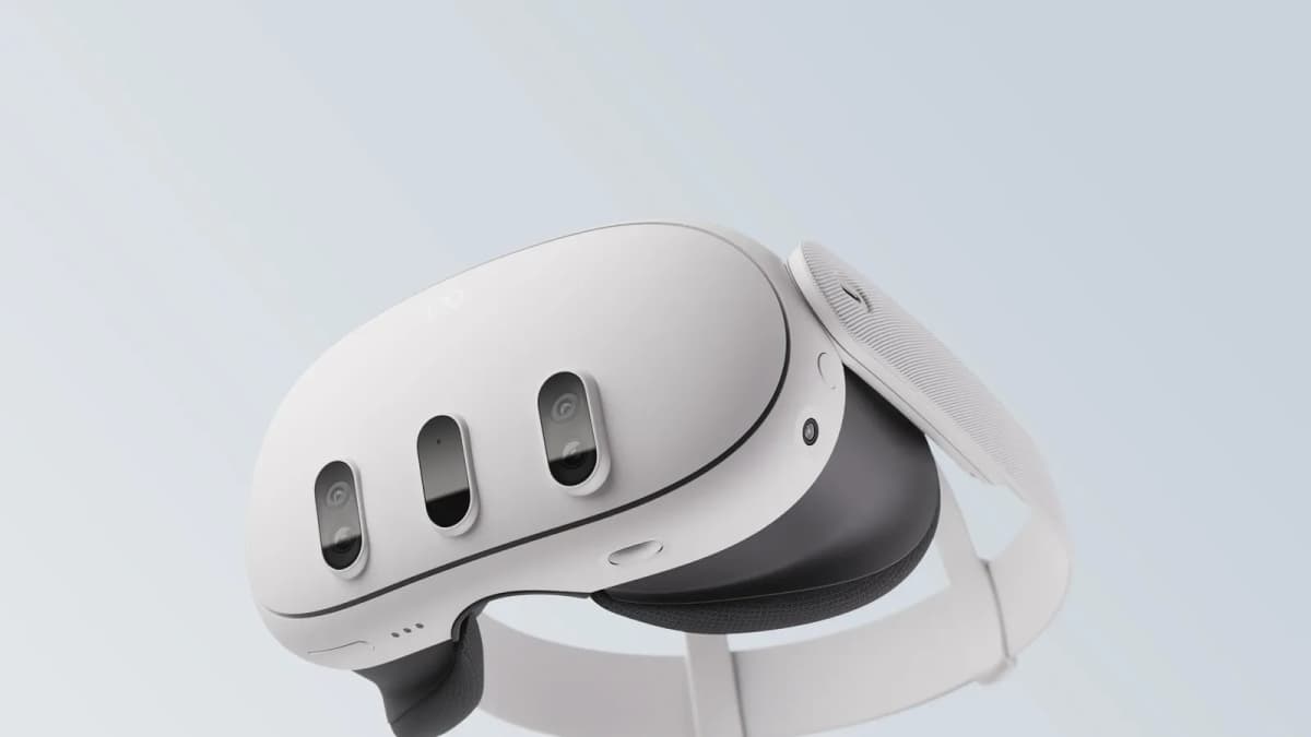 White Meta Quest VR headset with three front camera sensors and a white head strap, shown against a pale gray background