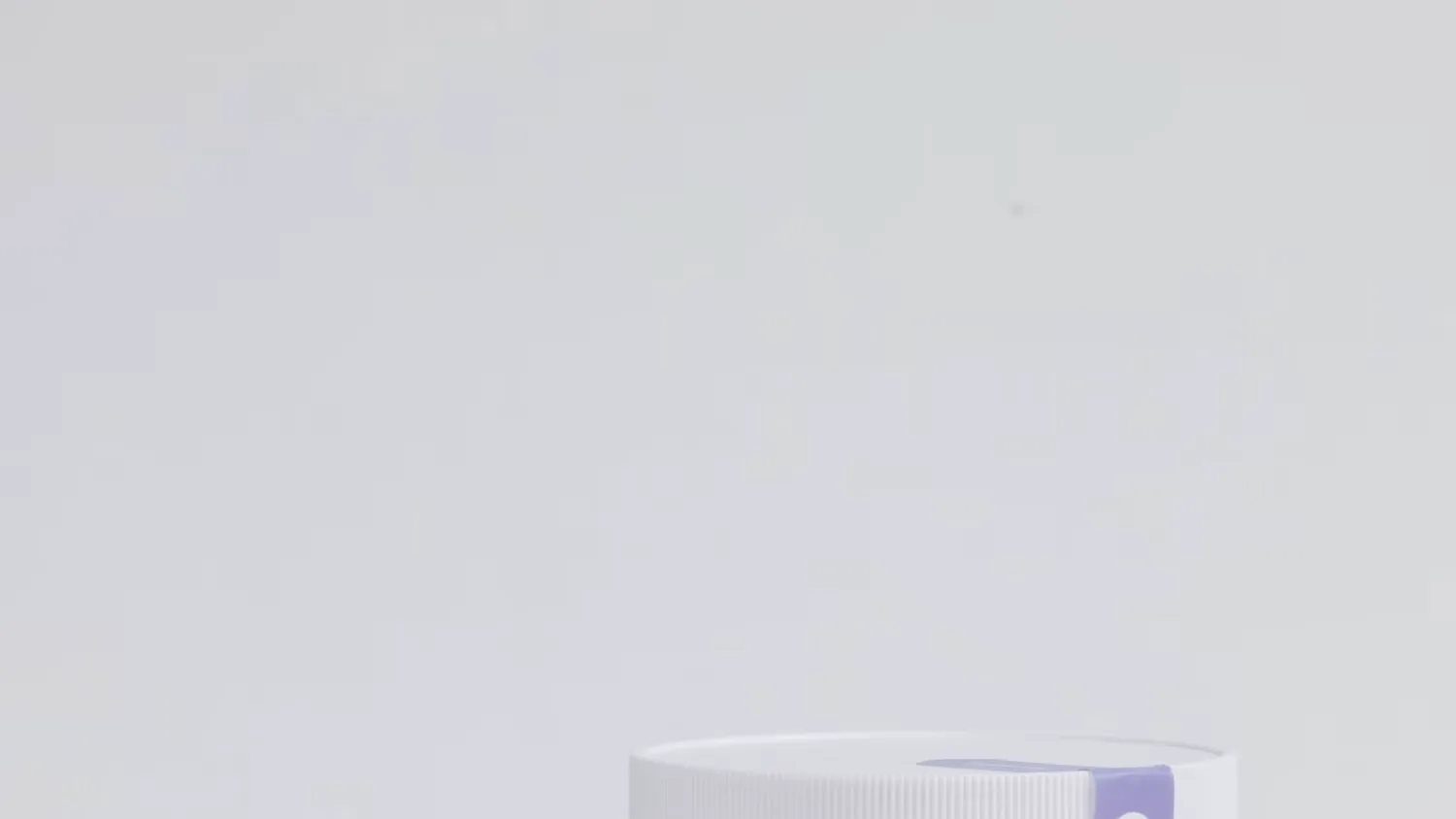Top of a white ribbed container lid with a lavender seal strip, against a plain pale gray background