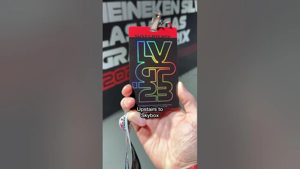 Hand holds a Las Vegas Grand Prix "SATURDAY" credential with a holographic logo, captioned "Upstairs to Skybox"