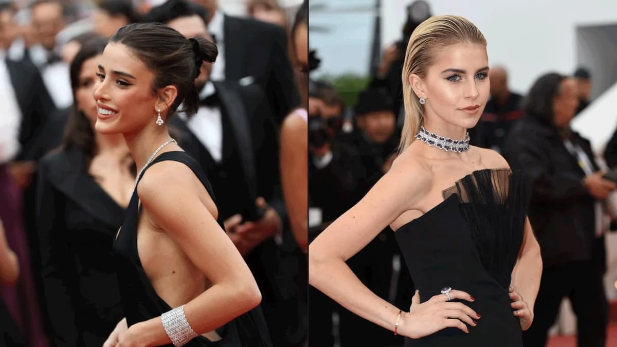 Two women in black gowns and diamond jewelry pose on a red carpet, one smiling in profile, one with hands on hips