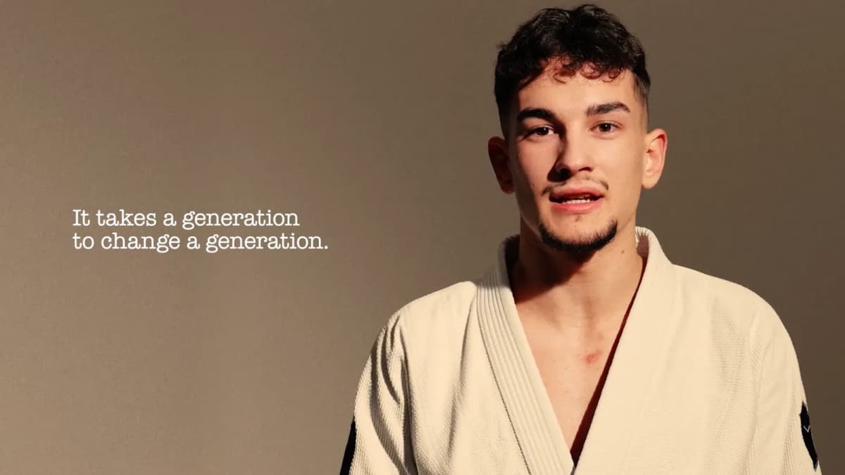 Young man in a white judo gi speaks to camera beside text "It takes a generation to change a generation."