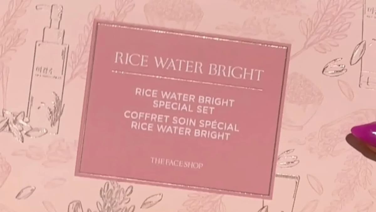 Pink-nailed fingertip beside a pink skincare gift box with botanical line art, labeled "RICE WATER BRIGHT SPECIAL SET"