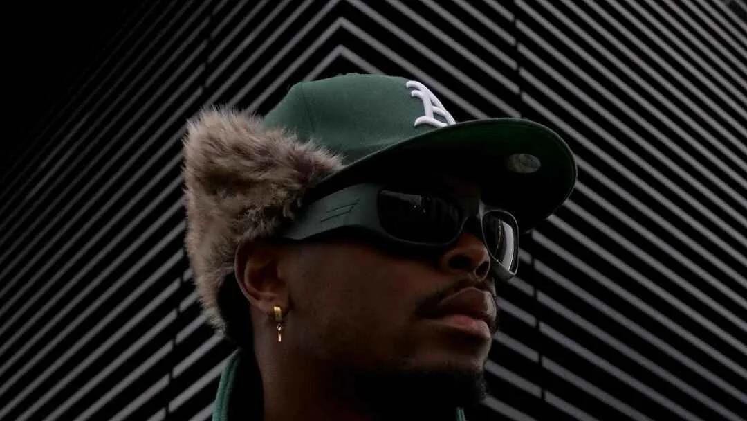 New Era, Anjo Alexandre in a green cap with fur ear flaps, sunglasses and a green adidas top