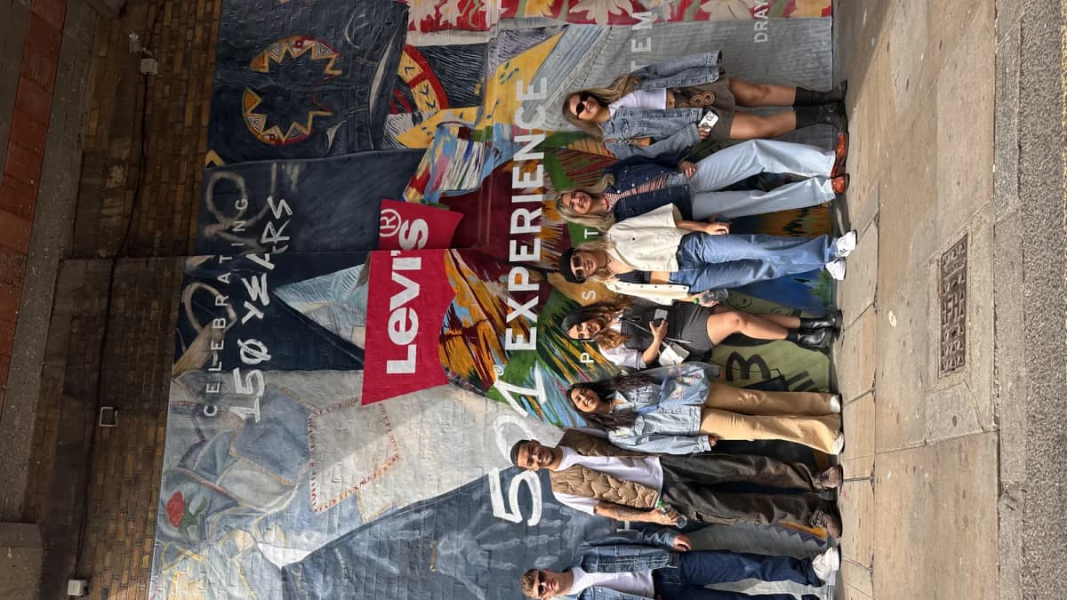 Seven young people in denim pose in front of a Levi's street mural that reads "CELEBRATING 150 YEARS"