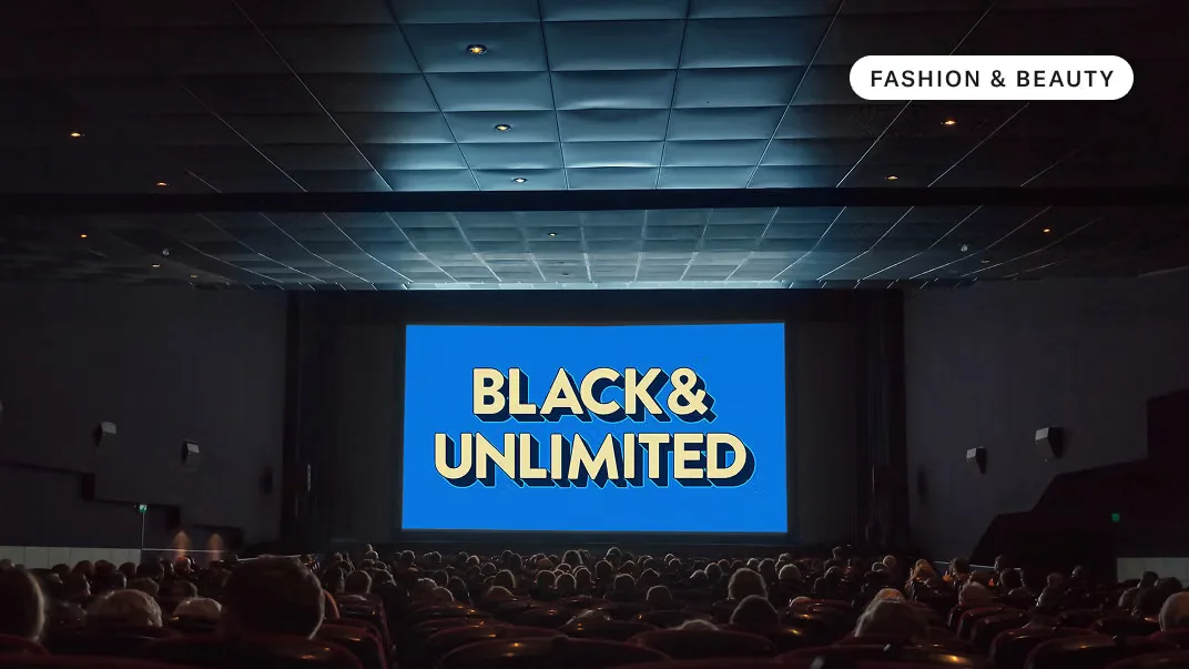 Audience in a dark movie theater facing a blue screen reading "BLACK& UNLIMITED"