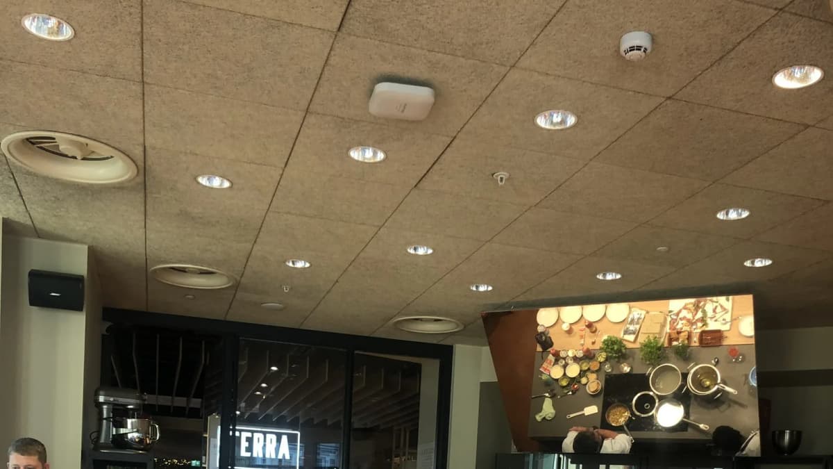 Cooking school with an overhead mirror showing a chef at a stove with pots, herbs and bowls; a "TERRA" sign behind