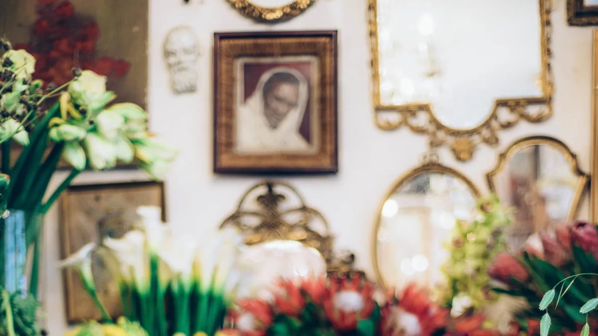 Blurred bouquets of red protea and white lilies before a wall of gilded mirrors, a plaster bust and a framed portrait