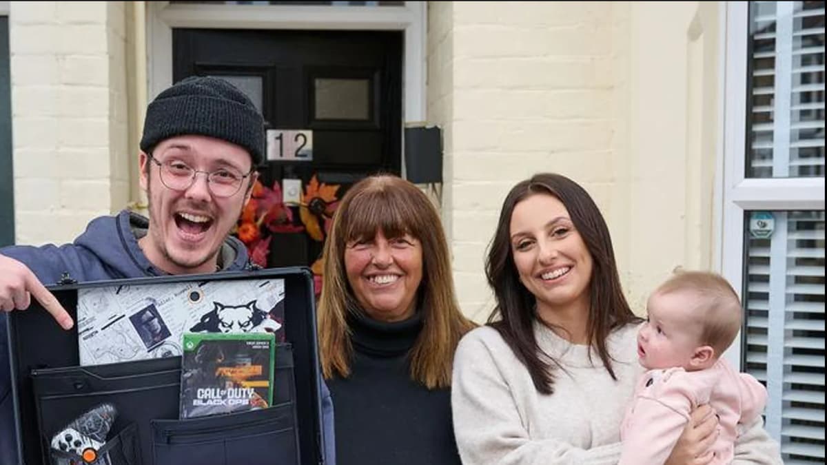 Man points at case holding Call of Duty: Black Ops 6 game and controller beside two smiling women and a baby by a door