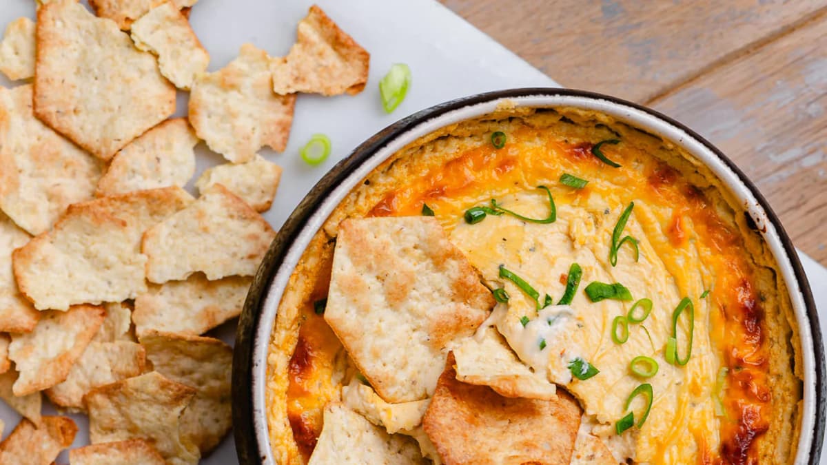 A crock of hot blue cheese dip, a wedge of Treasure Cave Blue Cheese, and crackers.