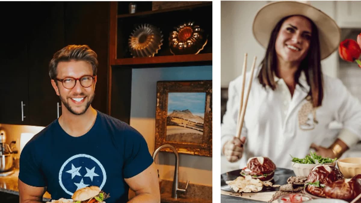 Smiling man in glasses holds a burger in a kitchen; woman in a wide-brim hat holds drumsticks over pretzel-bun burgers