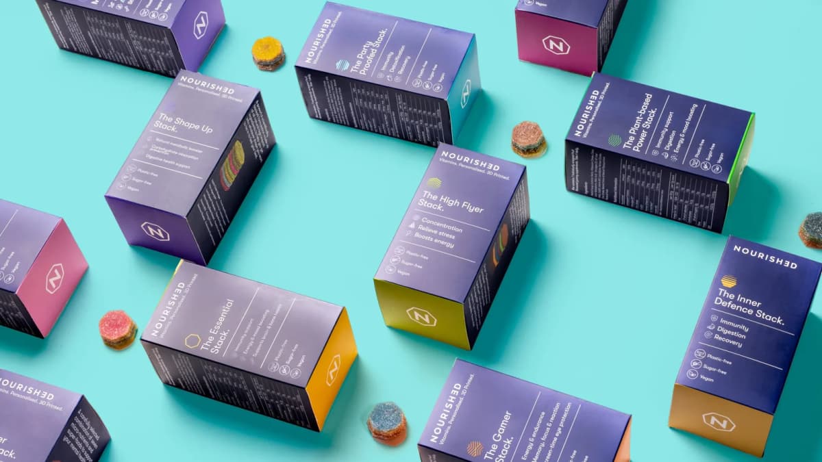 Purple Nourished vitamin boxes and layered gummy vitamins scattered across a turquoise surface
